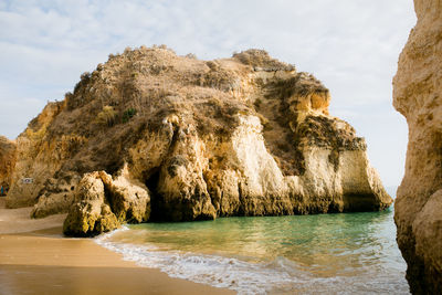 Rock formation on beach against sky