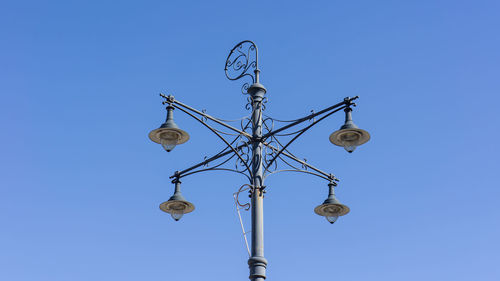 Low angle view of weather vane against clear blue sky