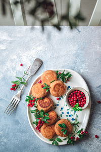 Breakfast set. russian cheese cakes on a craft ceramic plate with lingonberry over a blue background