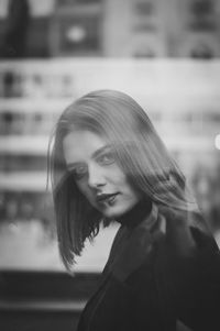 Close-up portrait of young woman looking through window