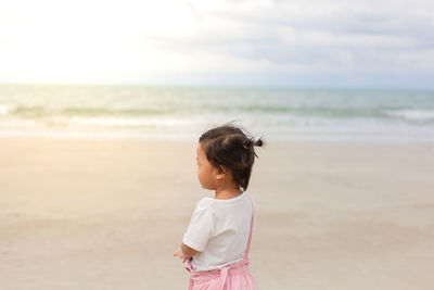 Girl standing on beach against sea