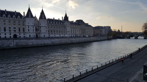 Bridge over river by buildings against sky