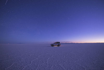 Vehicle on salar de uyuni at sunset