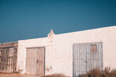 Low angle view of old church against clear blue sky through old gates