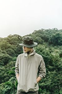 Young man standing against trees