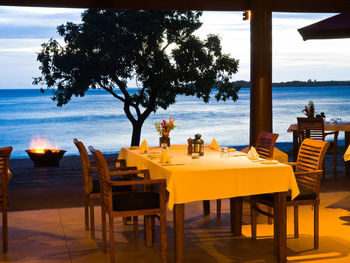 Chairs and tables at restaurant by sea against sky