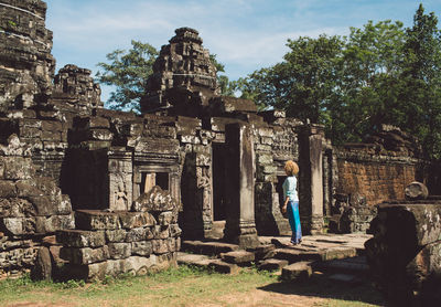 Side view of mid adult woman standing outside ankor wat temple