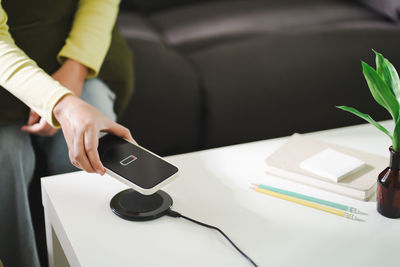 Midsection of man using smart phone on table