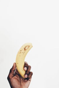 Close-up of hand holding apple against white background