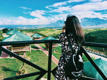 Woman with railing on mountain against sky