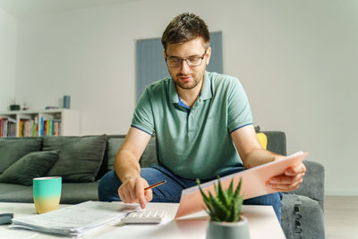 Young man using mobile phone while sitting on table