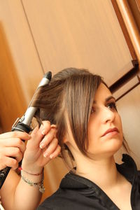 Cropped hands of hairdresser curling woman hair