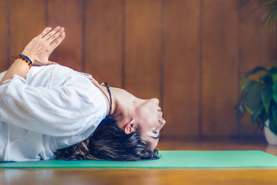 Side view of young woman doing yoga on exercise mat
