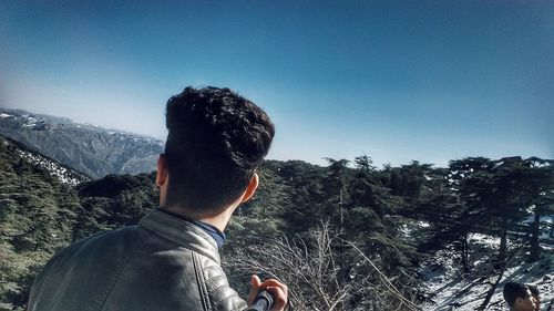 Woman photographing while standing against mountains