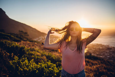 Portrait of woman standing against sea during sunset