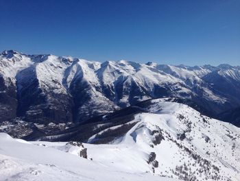 Scenic view of snow covered mountains against blue sky