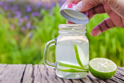 Midsection of person holding ice cream in jar on table