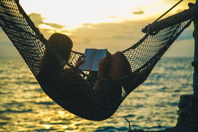 Close-up of woman holding fishing net against sky during sunset