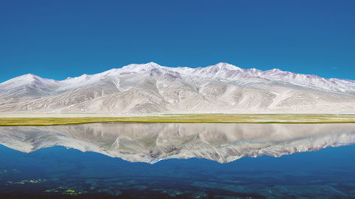 Scenic view of lake and mountains against clear blue sky