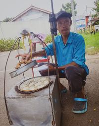 Full length portrait of man sitting on barbecue grill