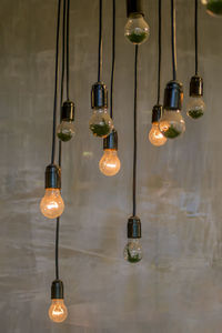 Illuminated light bulbs hanging against wall