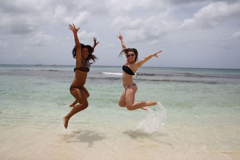 sea, water, leisure activity, sky, lifestyles, full length, enjoyment, fun, jumping, beach, vacations, mid-air, arms raised, person, happiness, shirtless, horizon over water, young adult