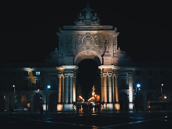 Statue in illuminated city at night