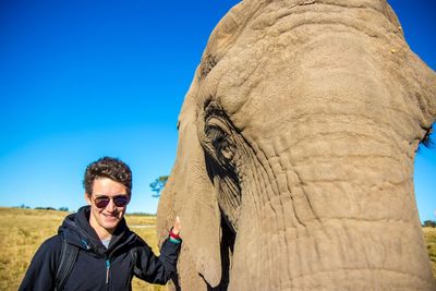 Portrait of man by elephant against sky