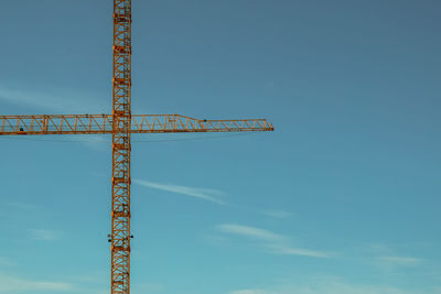 Low angle view of building cranes against sky