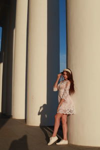 Full length of young woman standing by column