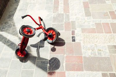 High angle view of red tricycle fallen on tiled floor