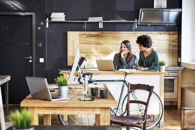 Two young women using laptop in modern office