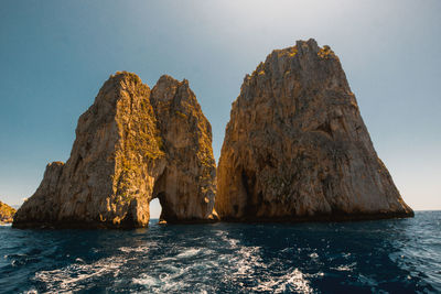 Rock formation in sea against clear sky