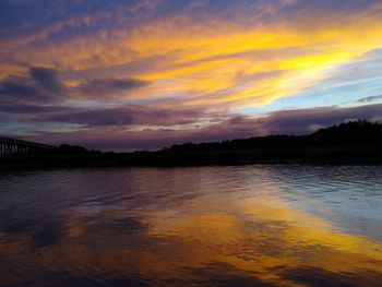 Scenic view of lake against dramatic sky during sunset