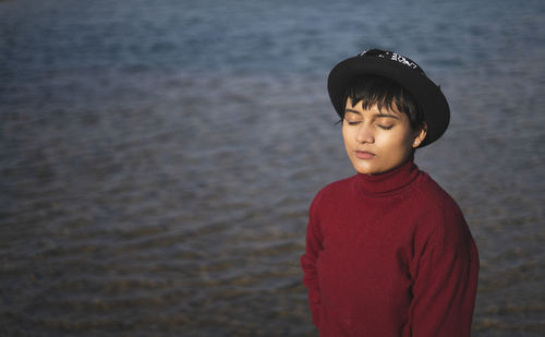 Portrait of an aesthetic looking girl wearing  sweater or sweatshirt with a hat captured near a lake