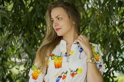 Portrait of beautiful young woman against plants