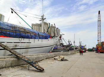 Sailboats moored at harbor against sky