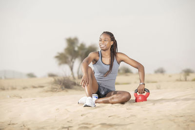 Full length of woman exercising in desert against sky