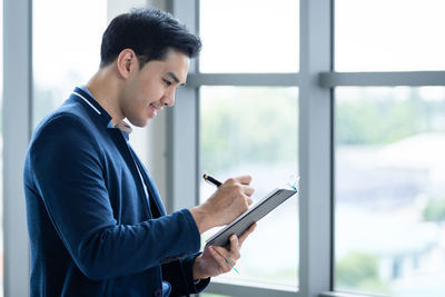 Side view of young man using mobile phone