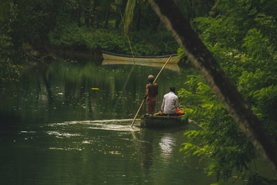 Rear view of men sitting on boat in lake