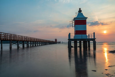 Pier over sea against sky during sunset