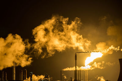 Low angle view of illuminated factory against sky at night