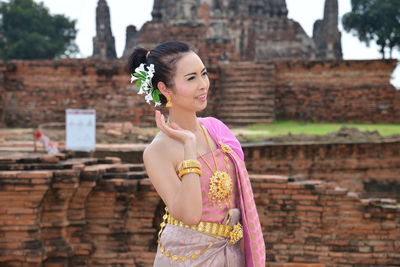 Smiling mature woman wearing traditional clothing standing against old monumental building