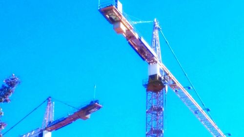 Low angle view of crane against blue sky