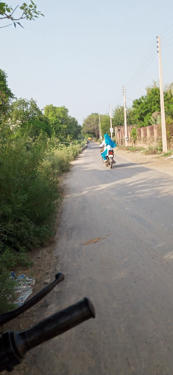 REAR VIEW OF MAN RIDING MOTORCYCLE ON ROAD