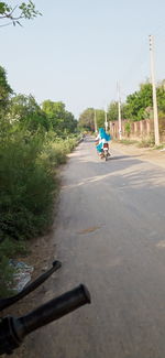 Man riding motorcycle on road against sky