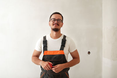 Portrait of young man standing against wall