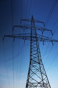 Low angle view of electricity pylon against clear blue sky