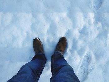 Low section of man standing on snow covered field