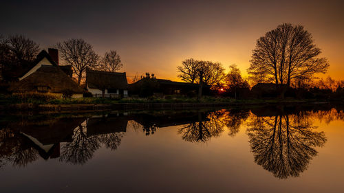 Reflection of trees in lake against sky during sunset